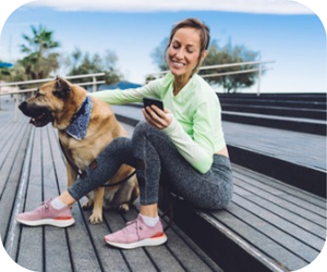 Women using phone, outside with her dog