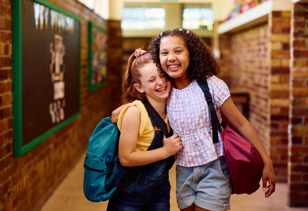 Two school girls hugging and smiling