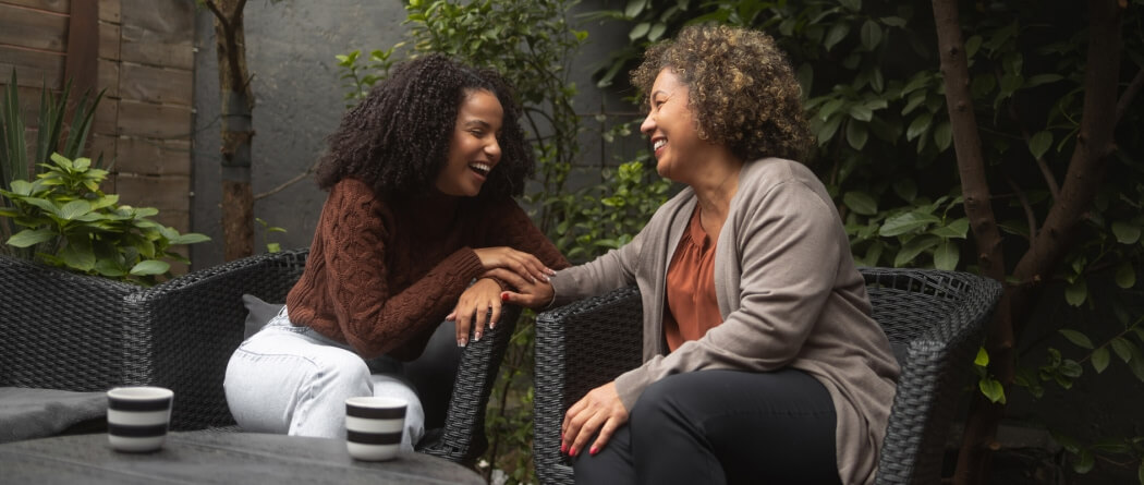 two women sitting together in outdoor chairs 