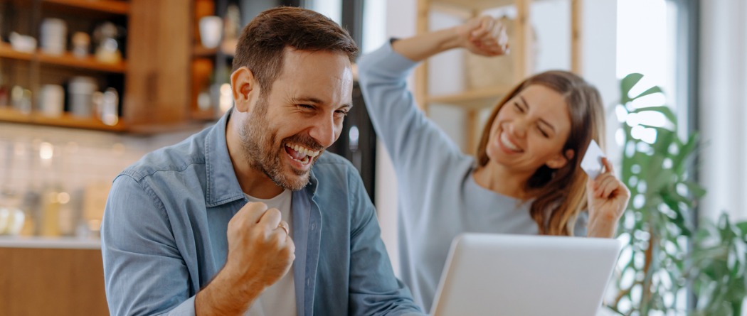Happy couple with laptop, celebrating