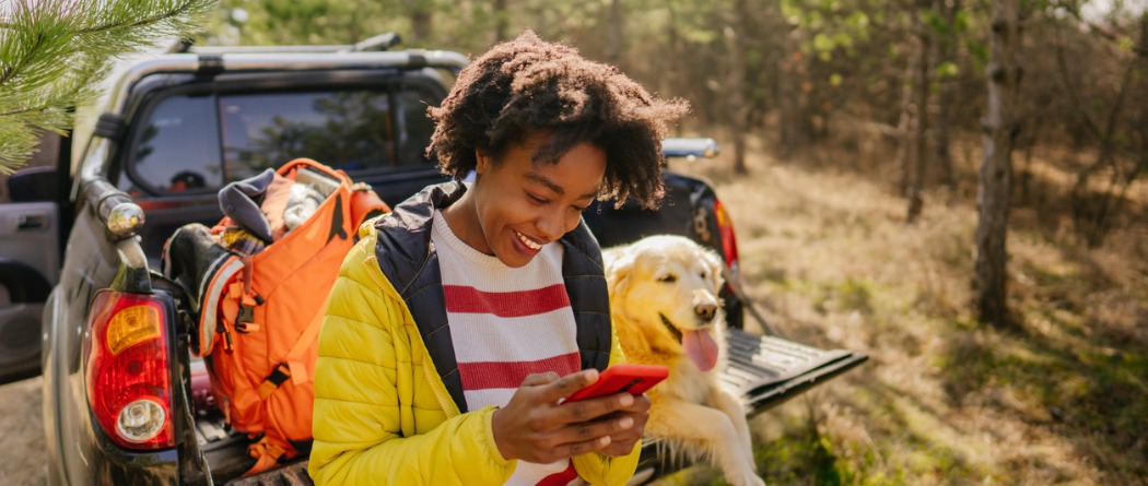 women camping with dog using mobile banking